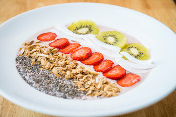 Smoothie bowl with strawberry, coconut, kiwi, granola and chia seeds