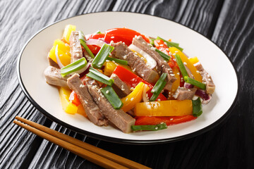 Beef tongue cooked with bell pepper, onion and sesame seeds close-up in a plate on the table. horizontal
