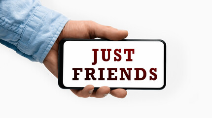 Closeup of a male hand holding Smartphone with text JUST FRIENDS on display