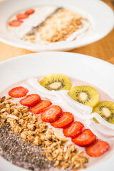 Smoothie bowl with strawberry, coconut, kiwi, granola and chia seeds