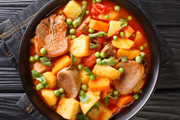 Slowly stewed beef tongue with vegetables close-up in a bowl on the table. horizontal top view from above