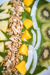 Smoothie bowl with kiwi, coconut, mango, pinapple, granola and chia seeds with green yogurt