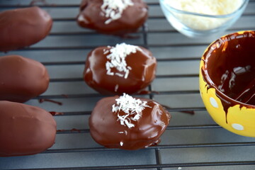 Medjool dates covered dark chocolate garnish with shredded coconut on cooling rack