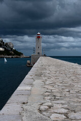 perspective sur une digue et un phare au loin par temps orageux avec des nuages très sombres