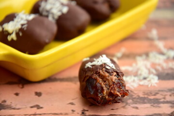 Medjool dates covered dark chocolate filled with almond butter garnish with shredded coconut. Selective focus