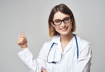 female nurse in medical gown gesturing with hands on light background cropped view