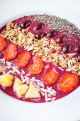 Smoothie bowl with blended berry yogurt, pinapple, grapes, strawberry, chia seed and almond flakes