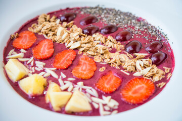 Smoothie bowl with blended berry yogurt, pinapple, grapes, strawberry, chia seed and almond flakes