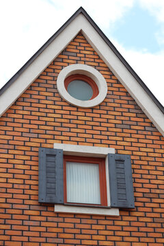 House roof facade, dormer window, shutters. Detail of the attic of a brick house.