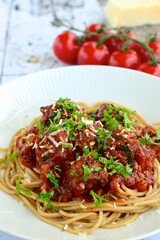 spaghetti with meatballs in tomato sauce garnish with parmesan cheese and parsley