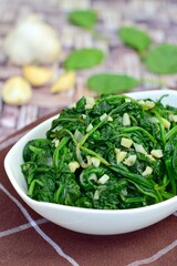 Sauteed garlic spinach. Healthy diet vegetarian. Blurred background