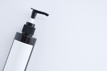 Plastic brown dispenser bottle with white label close-up on a white background. Place for text.