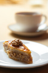 Traditional arabic dessert baklava and walnuts in white plate with a cup of coffee or tea ...