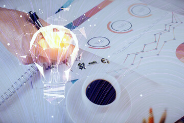 View of Bulb lamp idea concept icon on a futuristic interface with writing man's hand background. Double exposure.