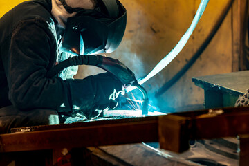 Electric and gas welder at work in a workshop at a welding enterprise.