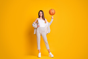 Fototapeta premium Photo of nice attractive sportive brown hair woman spinning ball playing basketball isolated over bright yellow color background