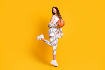 Fototapeta na wymiar Photo of nice attractive young woman hold basket ball play basketball wear tank-top pants sneakers isolated on yellow color background