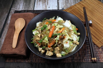 Fried and stirred Korea instant noodle with cutting fresh cabbage, carrot, Chinese celery, corn and tofu on the plate. Famous vegetarian menu in Asia restaurant. High fiber and vitamin food.