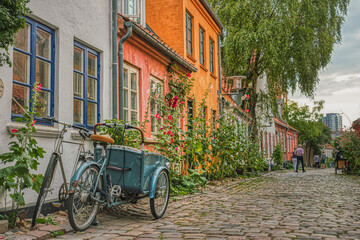 On a summer day a typical Danish Cargo bike, better known as Christiania Bike, is parked at the entrance of a house in a cosy, cobbled street conveying coziness and cultural concept - Aarhus, Denmark - obrazy, fototapety, plakaty