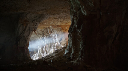 Photo of the cave. Darkness, pierced by a ray of light. Frightening atmosphere.