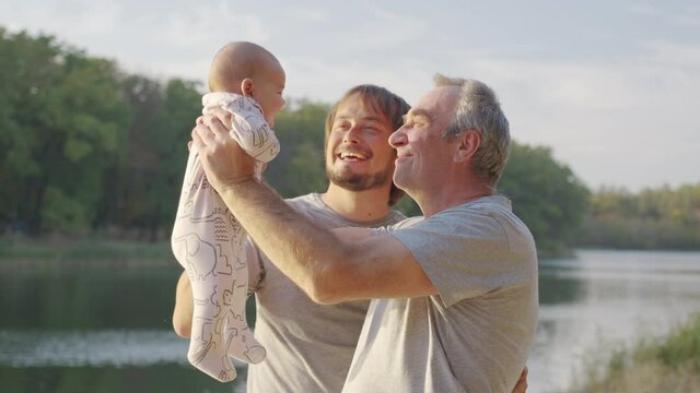 Three generations of men. Grandpa, father and little grandson. Sunset, the bank of the river.