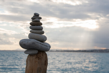 cairn fait de galets posé en équilibre sur un poteau en bois face à la mer