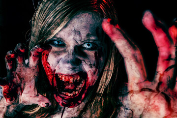 Studio portrait of a female vampire of zombie looking at camera. Black background.