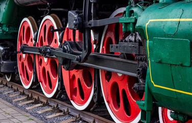 Old black and red retro steam locomotive wheels at the railway station. Vintage train staying on the railroad.