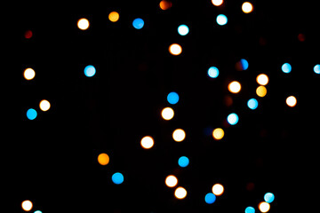 A brilliant glowing background side on black. The glitter light bokeh for the New Year and other holidays. Place for text copyspace.