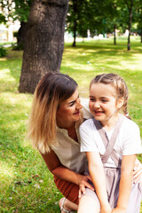 young pretty mother walking with little cute daughter outside in green park, lifestyle poeple concept