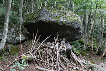 大きな岩の下に立てかけられてある枝木 (日光白根山にて)