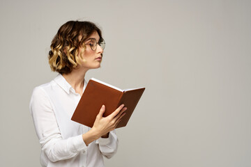 woman with notepad in hands business work beige background glasses hairstyle