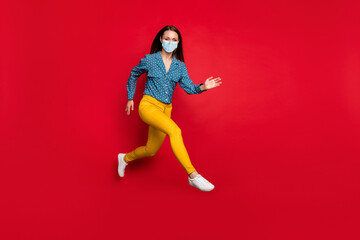 Full length view of attractive fit cheerful girl jumping running active motion wear mask isolated bright red color background