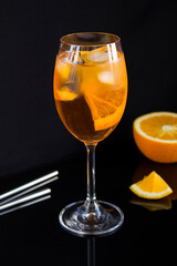 Aperol spritz cocktail in wine glass on the black background. Location vertical.