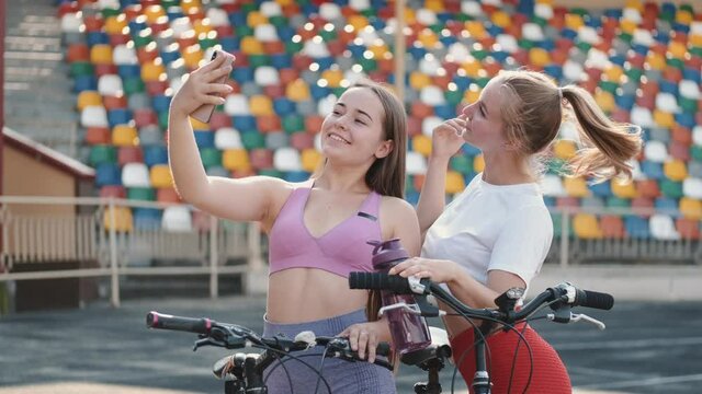 Two sporty women doing selfie after marathon or workout fitness. The women standing with bicycles.