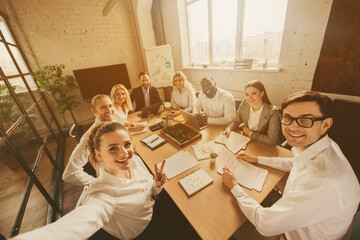 Photo of business people eight diversity age race colleagues sit table share anti crisis crash ideas team professionals making selfies teambuilding showing v-sign symbol office indoors