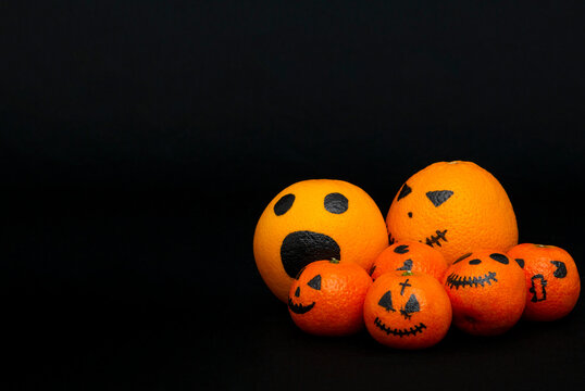 oranges and mandarins painted like a halloween pumpkin, happy halloween citrus