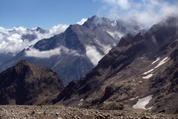 Mountain landscape with glaciers and clouds. View from the Koshtan mountain pass (3513 meters above sea level). Caucasus, Russia.