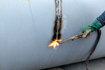 The worker is cutting to metal plate with manual flame cutting process. Oxy-fuel welding,...