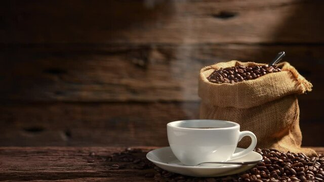 Cup of coffee with smoke and coffee beans on old wooden background.