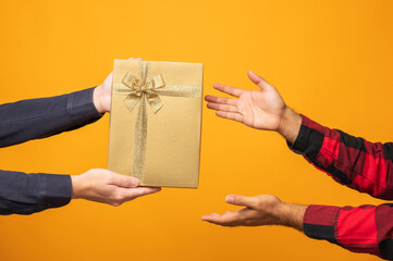 Close up hands giving the present gift box in christmas day on yellow background. Merry christmas...