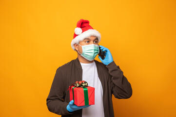 Delivery man in christmas uniform carrying gift box using smartp
