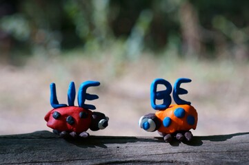 The inscription love in German. Next to it are two figures of ladybirds made of plasticine.
