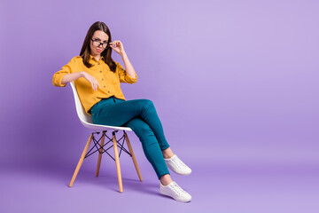 Full length photo of girl sit chair crossed legs take off specs wear yellow shirt blue pants...