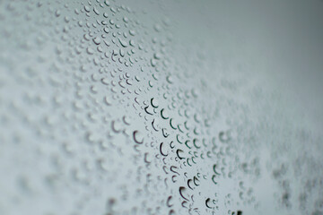 multiple rain drops on a grey window during a thunder storm