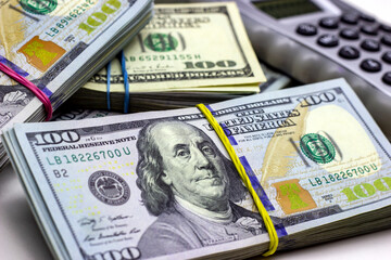 Fototapeta premium Dollar usa packs with gray calculator on white background. Money accounting and finance savings analyzing concept.