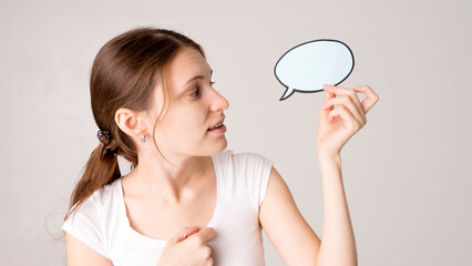 mid adult woman holding blank speech bubble on white background. Horizontal shape, front view, waist up, copy space