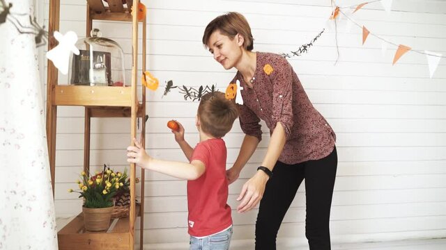 Mom and son get ready for halloween decorate the room.
