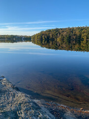 Autumn nature landscape, lake, trees, colorful, foliage, Reflections in calm water. Photography taken in October in Sweden. Blue sky background, copy space and place for text.