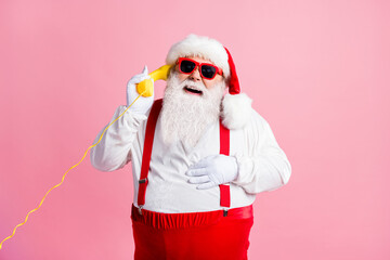 Fototapeta na wymiar Portrait of his he nice attractive cheerful cheery glad Santa father talking on yellow phone contact center communication laughing good joke isolated over pink pastel color background